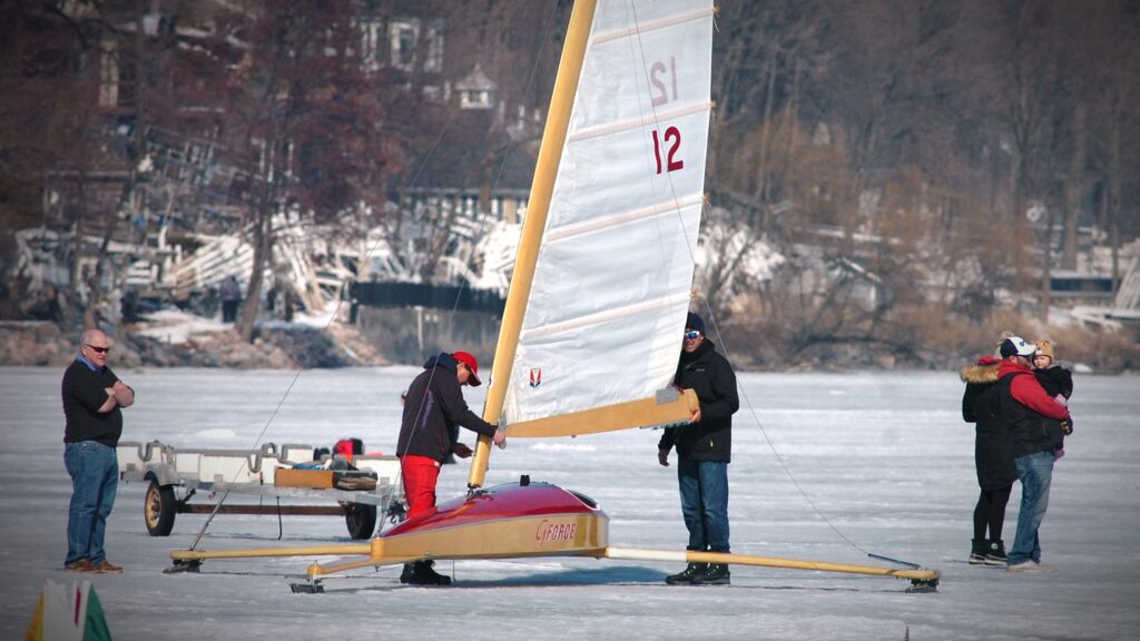 Ice boaters adjust their rigging, hoping the wind picks up.